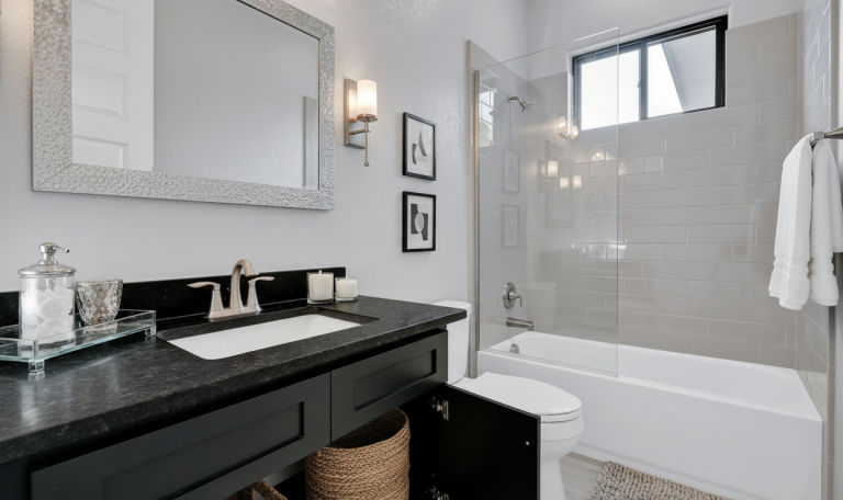 Elegant bathroom with glass shower, black countertop, and neutral tiles.